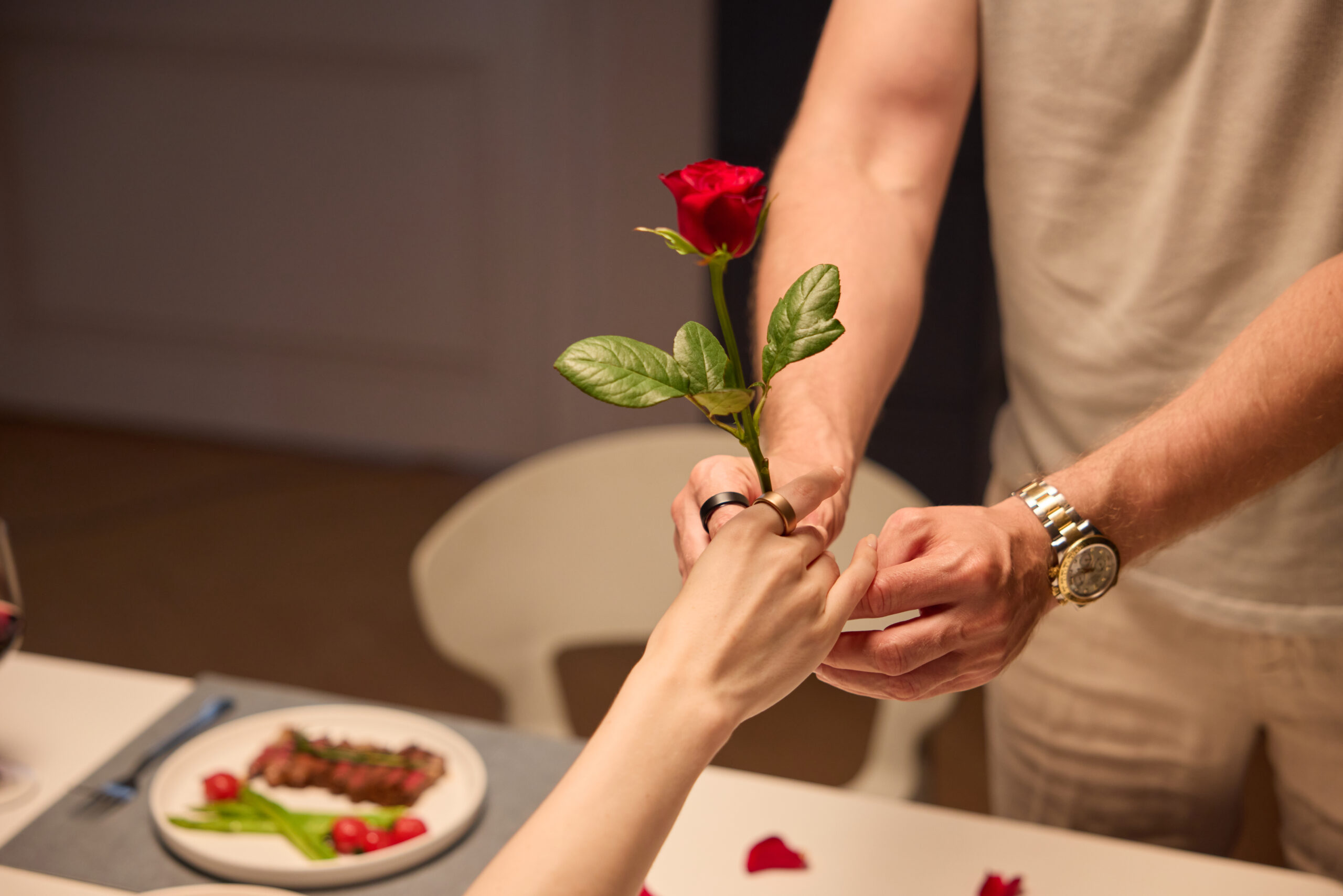A romantic couple wearing Doni smart rings, with the man giving the woman a red rose.